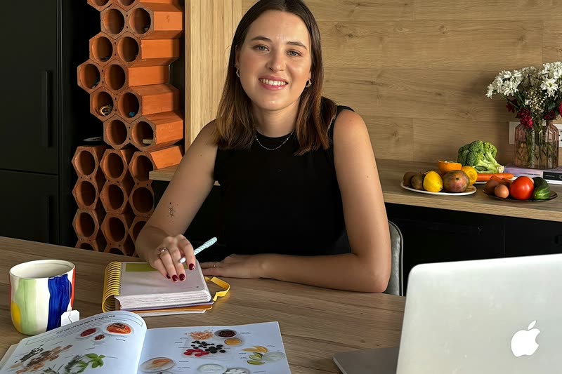 Nutritionist Marta Casas at her desk with a laptop and a book of food photographs