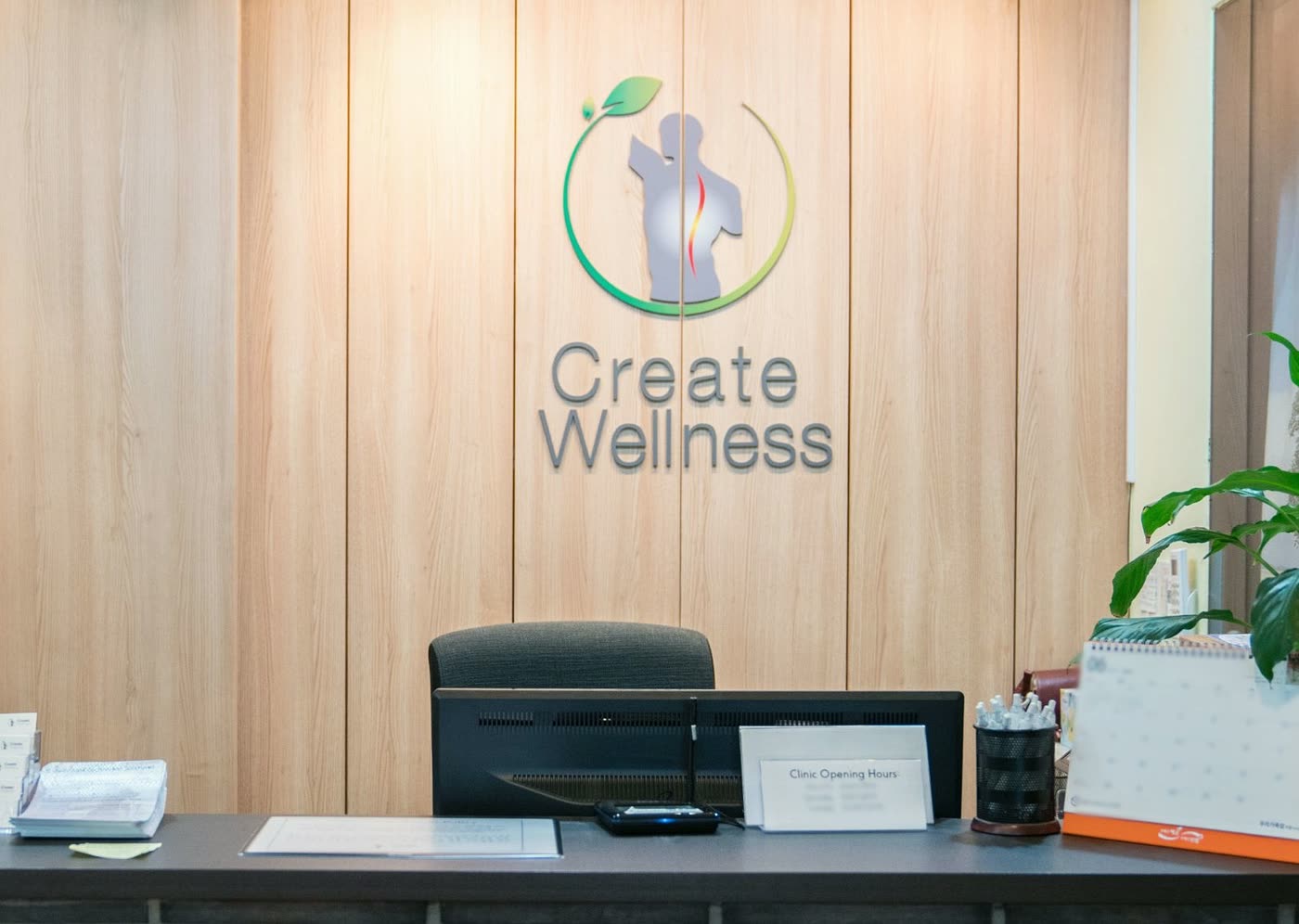 The reception desk of the Seoul clinic in Itaewon, under the Create Wellness Center logo on the wood-panelled wall