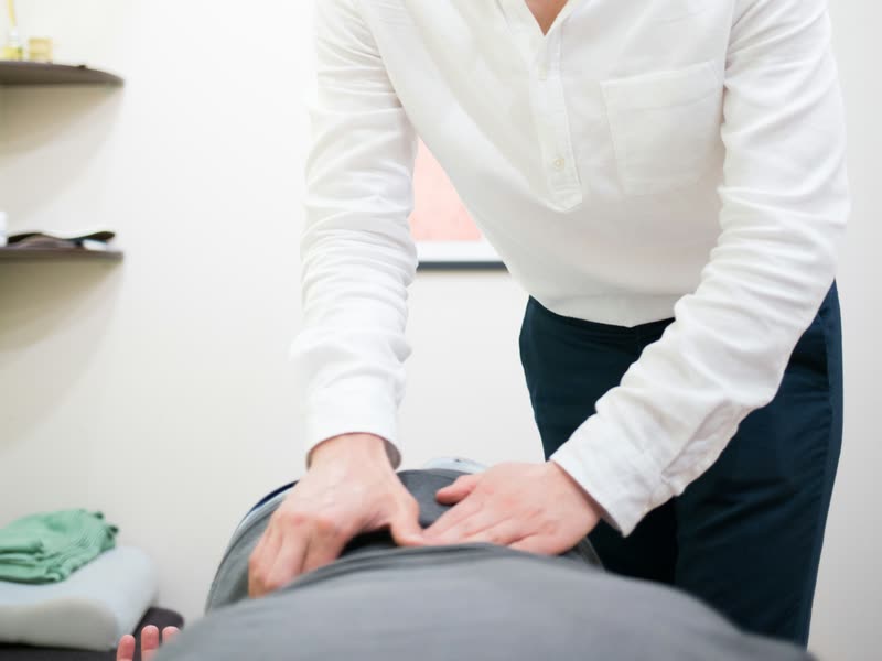 Chiropractor's hands delivering a spinal adjustment to a patient lying face down on a treatment table