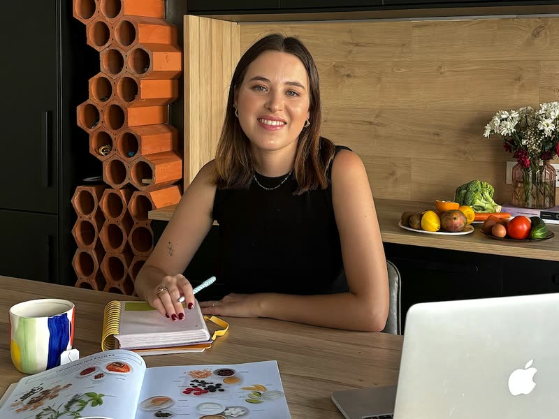 Nutritionist Marta Casas reviewing a nutrition plan at a desk with a laptop and a food reference book