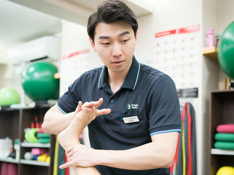 Rehabilitation specialist holding a patient&rsquo;s raised foot during hands-on treatment at Create Wellness Center in Itaewon