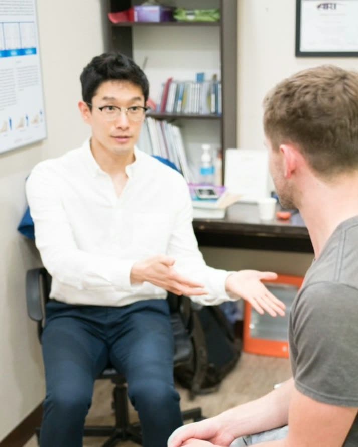 Chiropractor Hyunjin Kim, DC, explaining a treatment plan to a patient in the consultation room